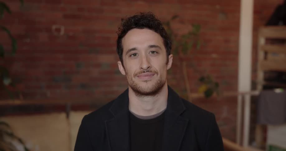 A man smiles while standing indoors