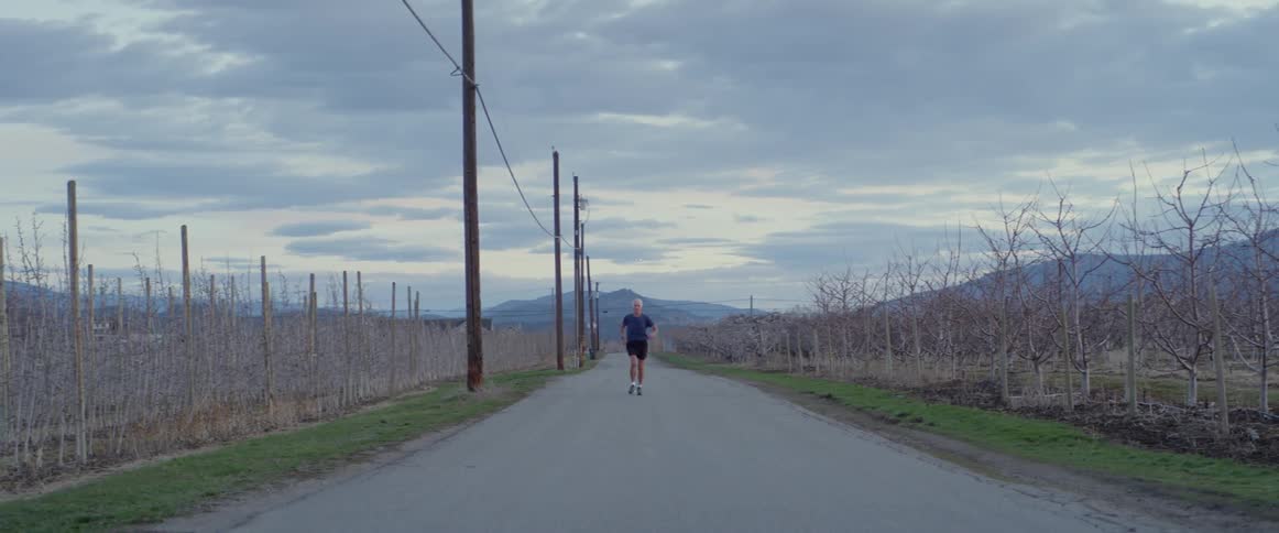 Man jogs down a road next to some hydro poles