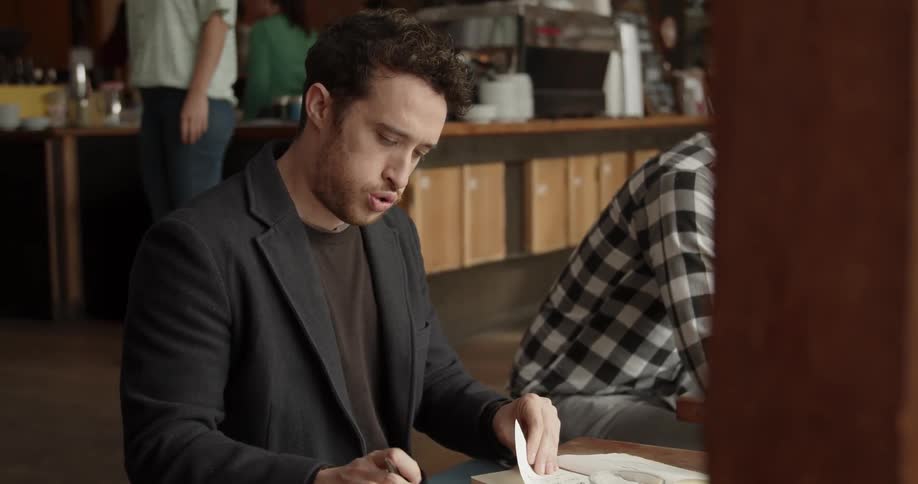 Man writes in a notebook in a coffee shop