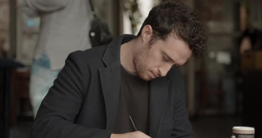 Man sits at a desk writing in a notebook