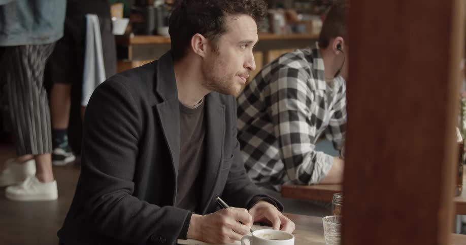 A man writes in a notebook inside a cafe