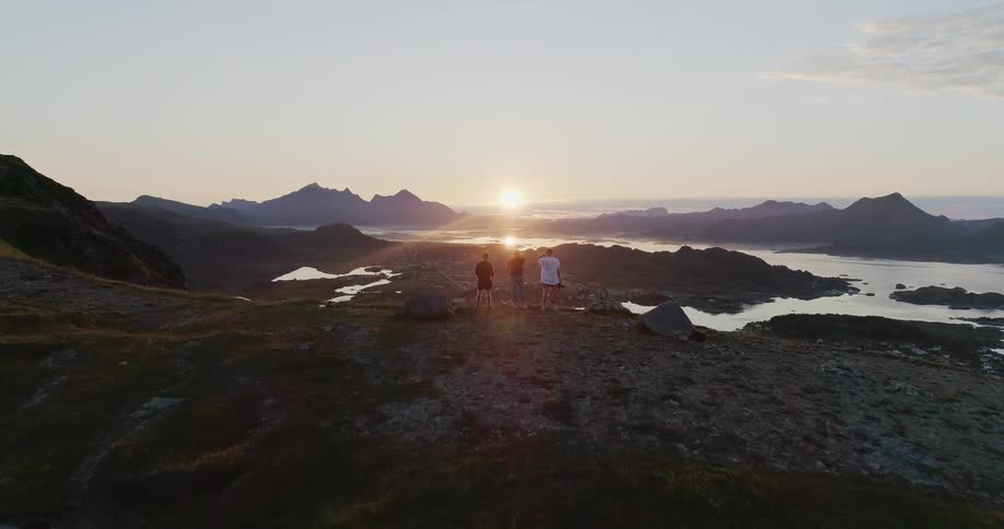Hikers stand on a mountain ridge at sunset