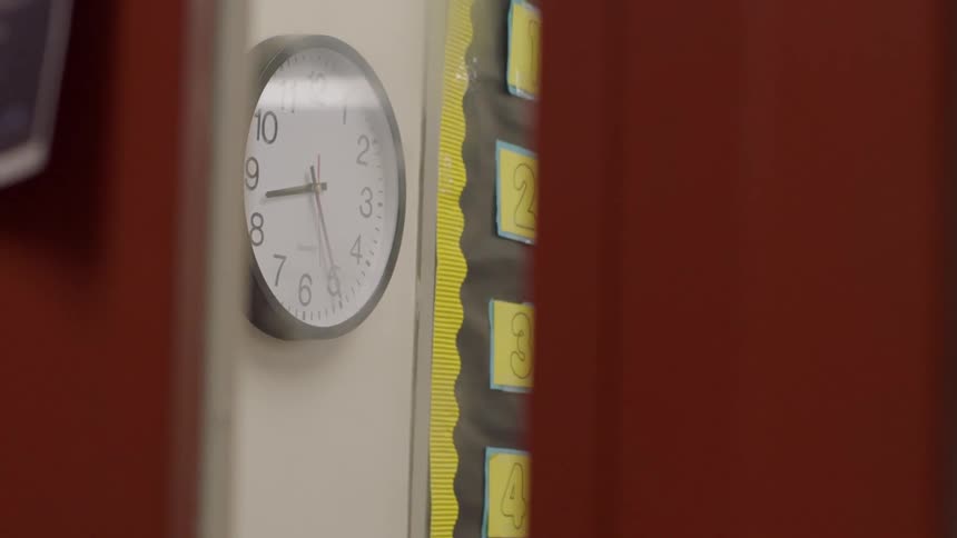 A clock hangs on a classroom wall