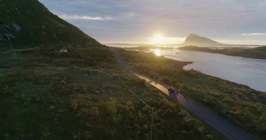 A car drives next to a lake at sunset