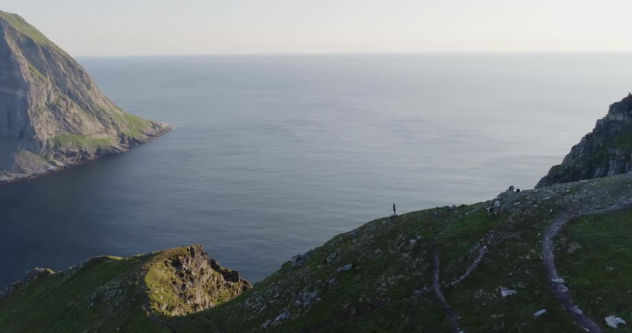 The person stands on the cliff overlooking the water