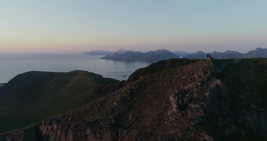 People are standing on a cliff near the shore