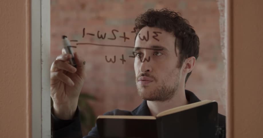 A man writes a math equation on a window