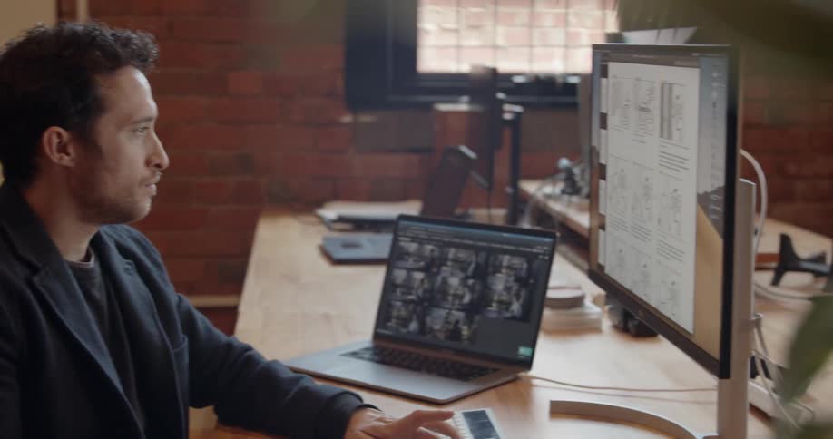 Man sits at a desk typing on a keyboard and looking at a monitor
