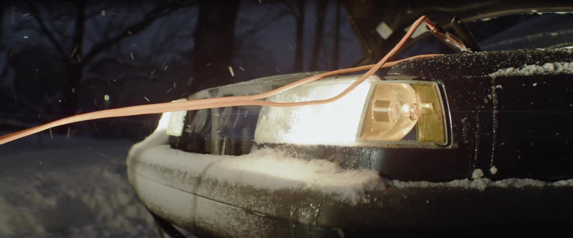 The car is sitting in the snow jump starting another