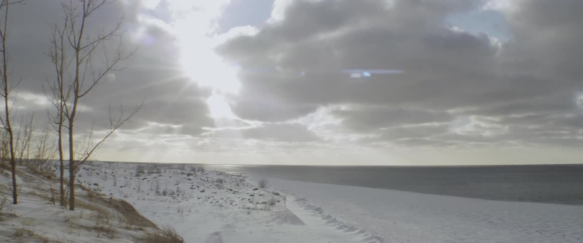 The sun is rising high into the clouds of the shore