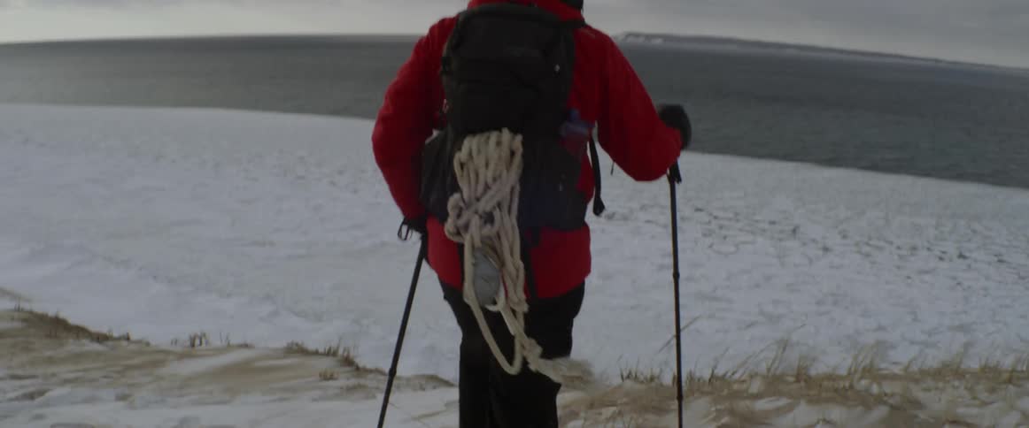 Man snowshoes next to a lake