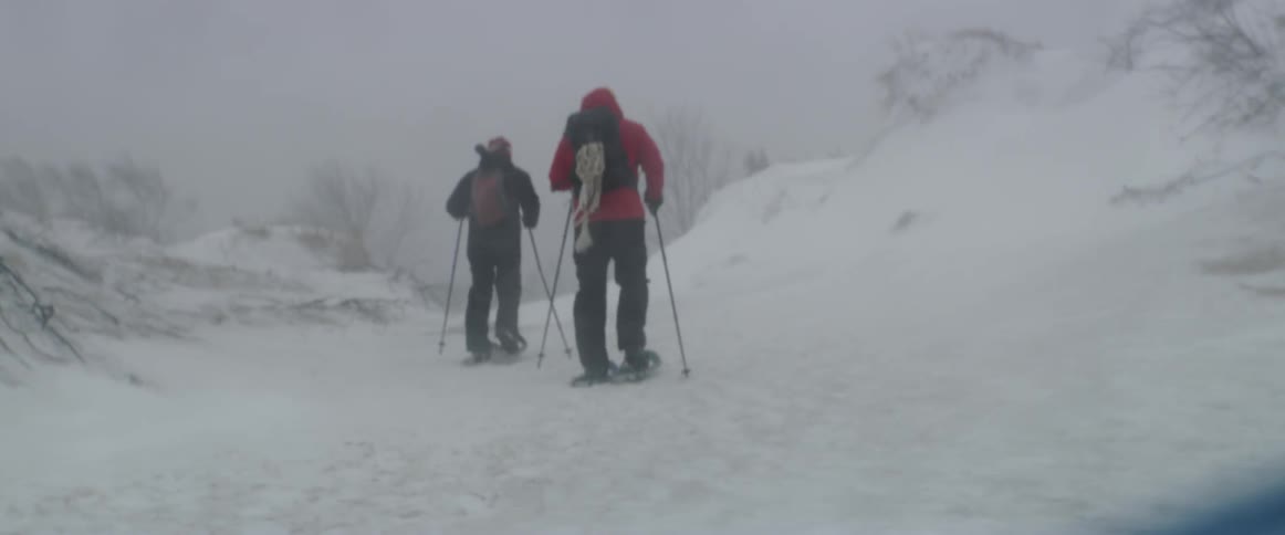 Two people snowshoe during a storm