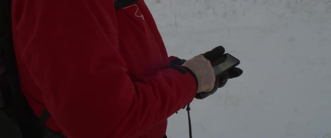 A person is checking their phone in the snow