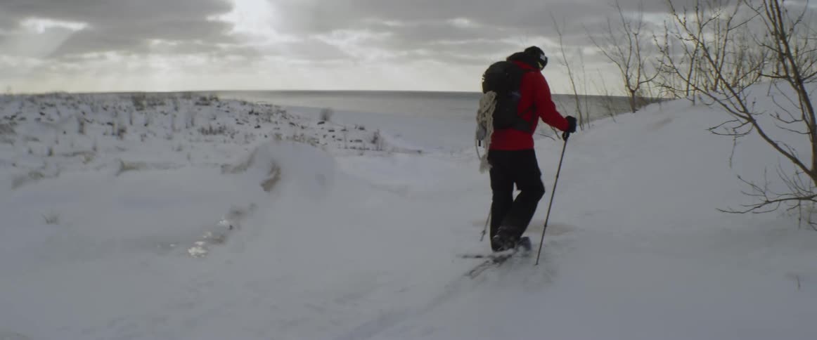 The man travels uphill in the snow with snowshoes