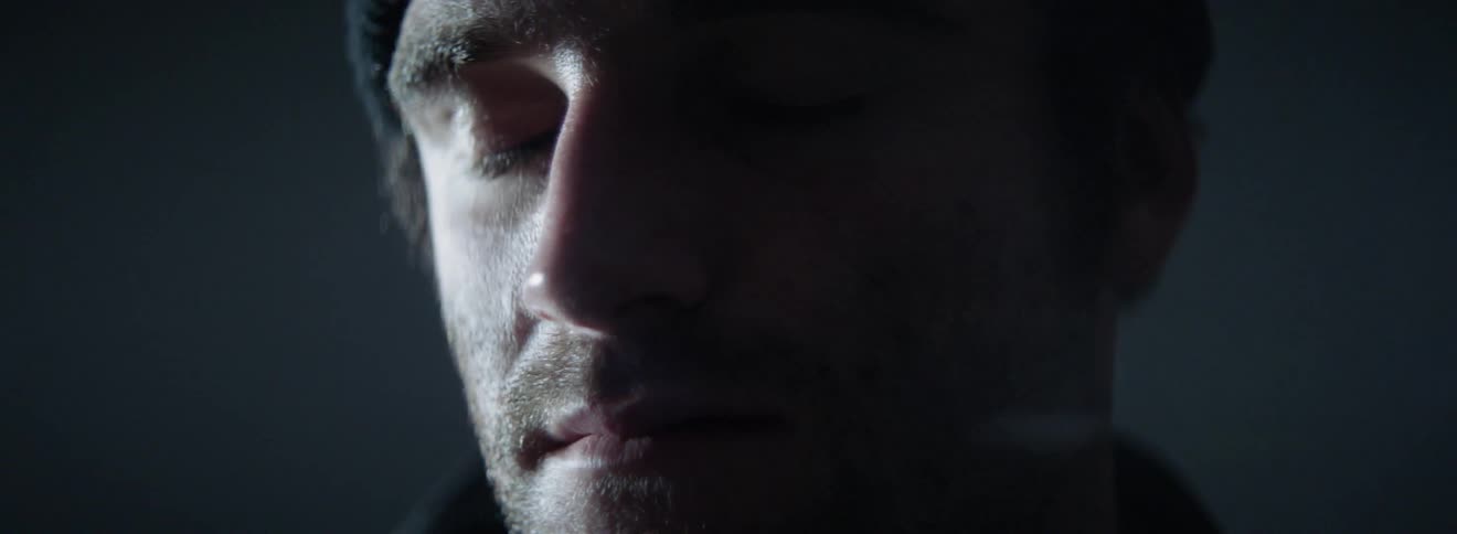 The man is in the dark room with his eyes closed