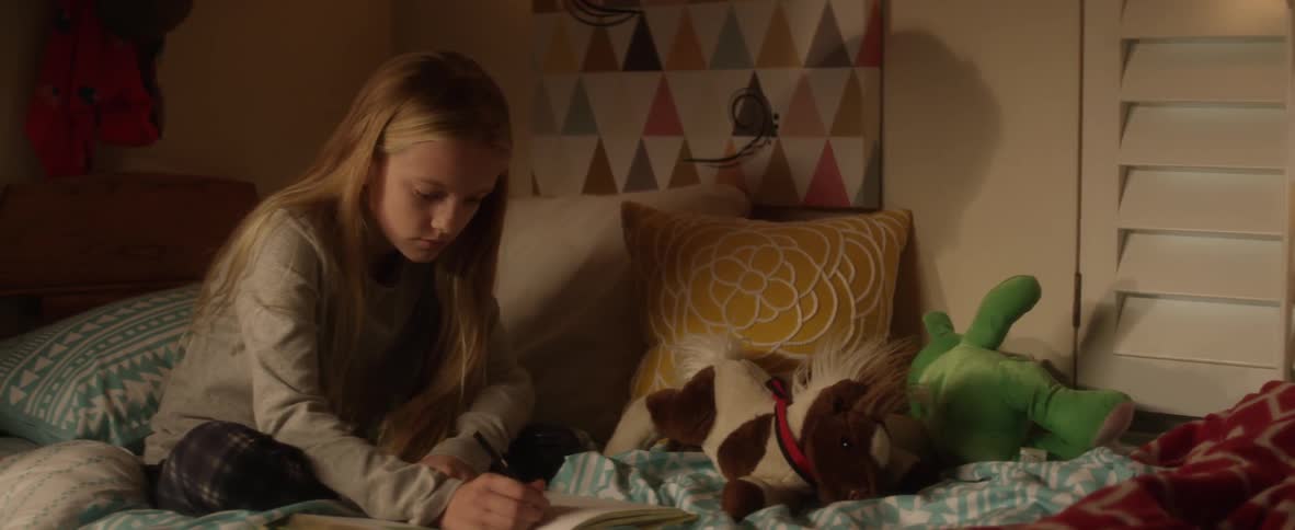 A child is drawing on their bed