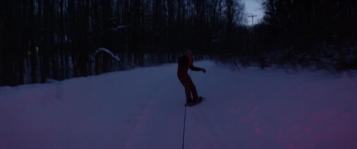 A man snowboards while being pulled by a vehicle
