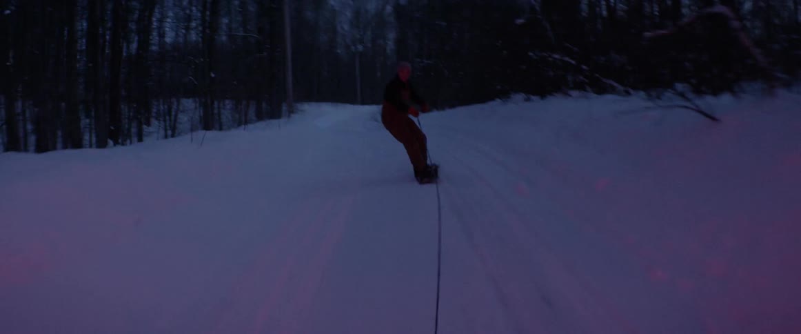 A snowboarder is pulled behind a truck