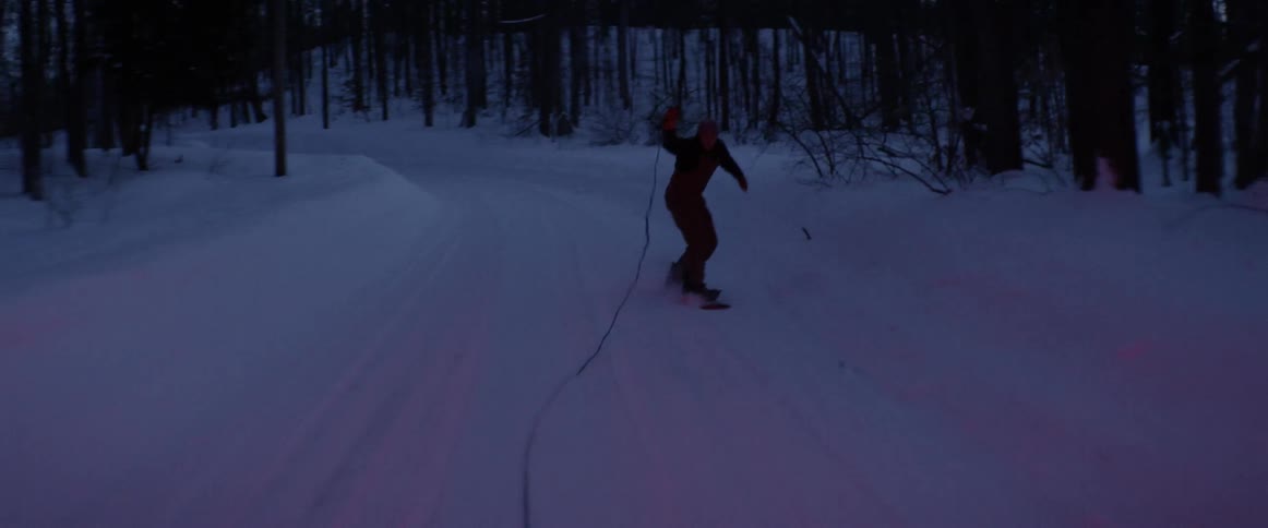 A snowboarder is pulled behind a truck