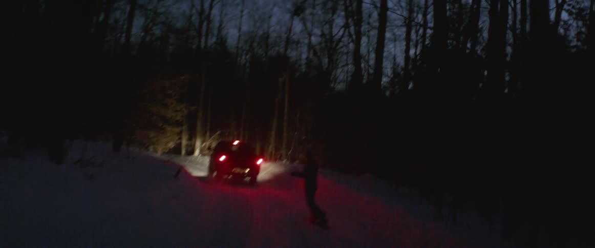 A truck pulls a snowboarder through a forest