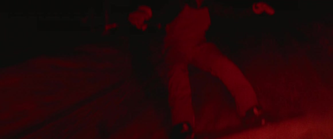 A man is snowboarding at night while being pulled by a truck
