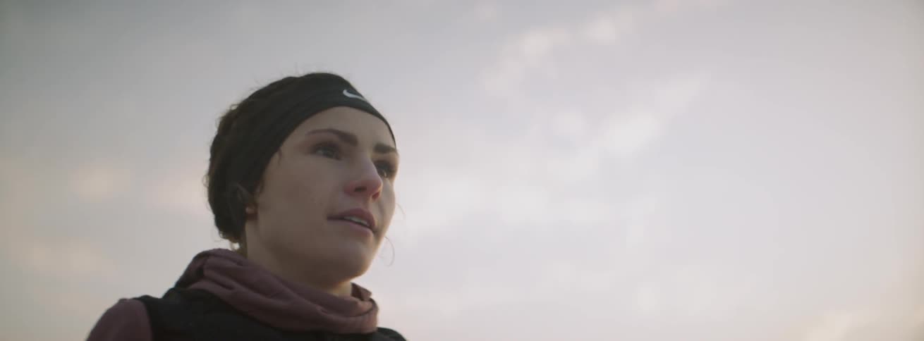 A woman smiles outside on a cloudy day