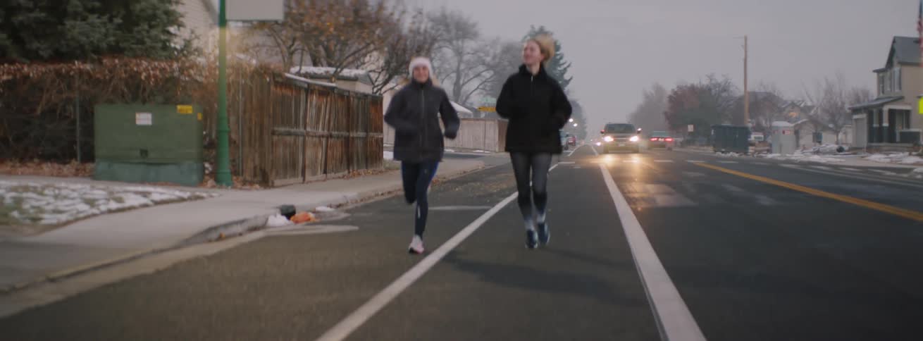 Two women smile as they run down the road