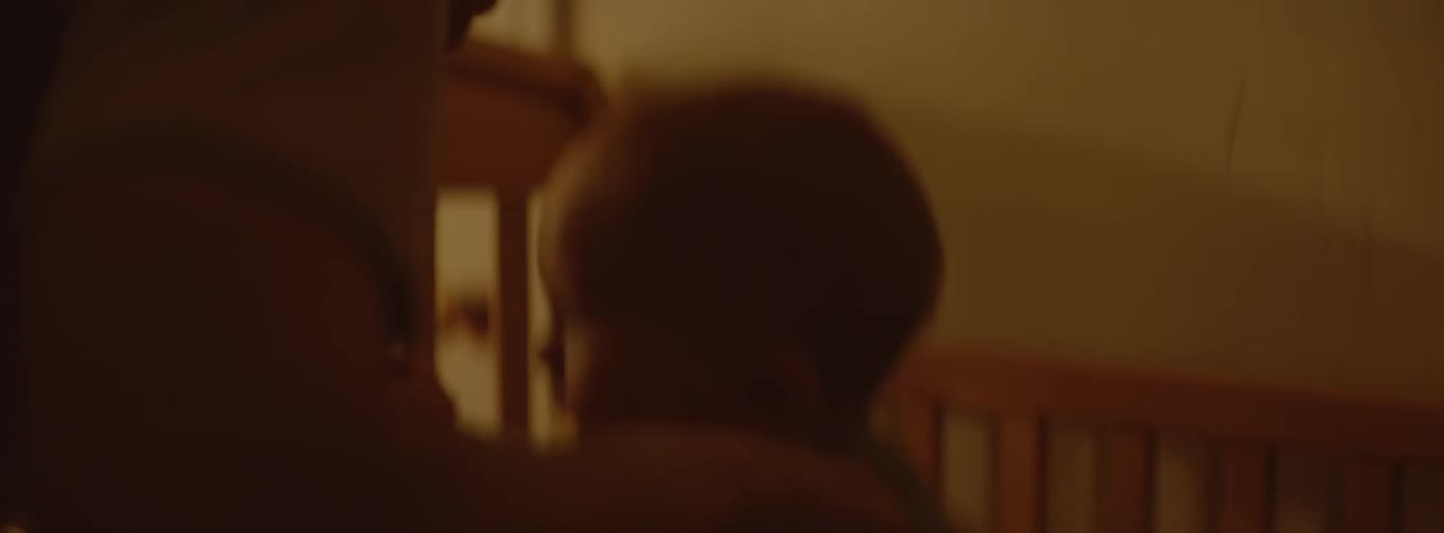 A baby jumps in his crib as he holds onto his parent's hands
