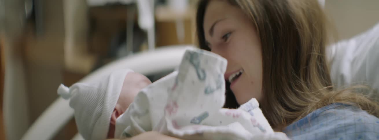 A woman cradles her baby and smiles