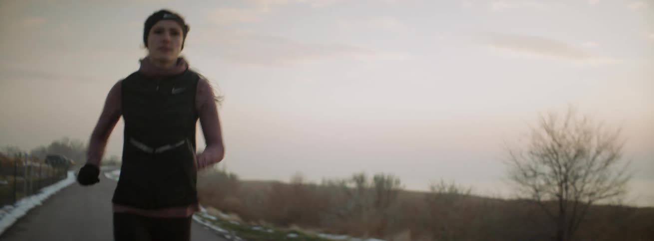 A woman is jogging on a pathway outside in winter