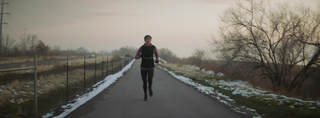 Woman jogs on a rural road at sunset