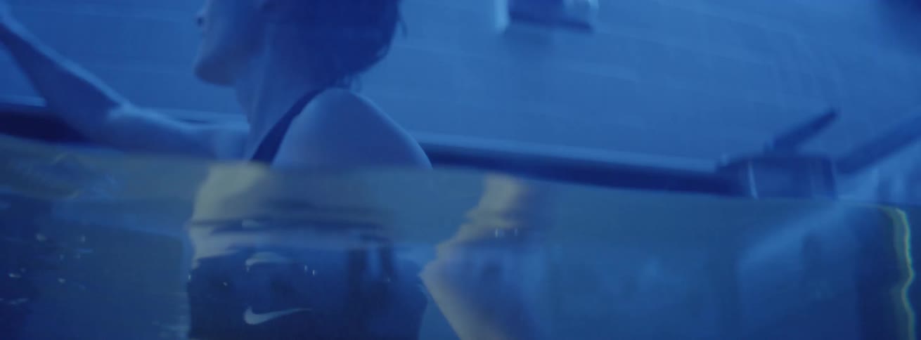 A woman stands in the water leaning on a bar