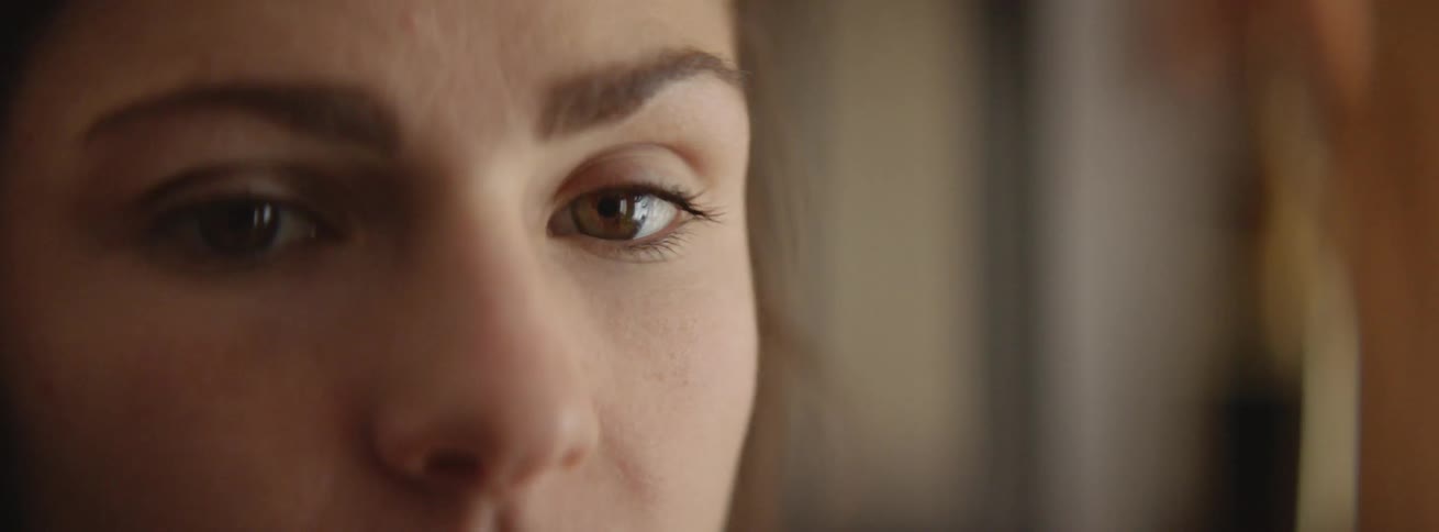 A woman looks slowly to her side while blinking