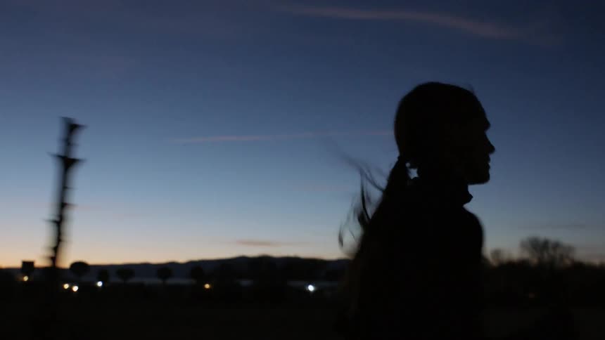 A woman runs at dawn past a field