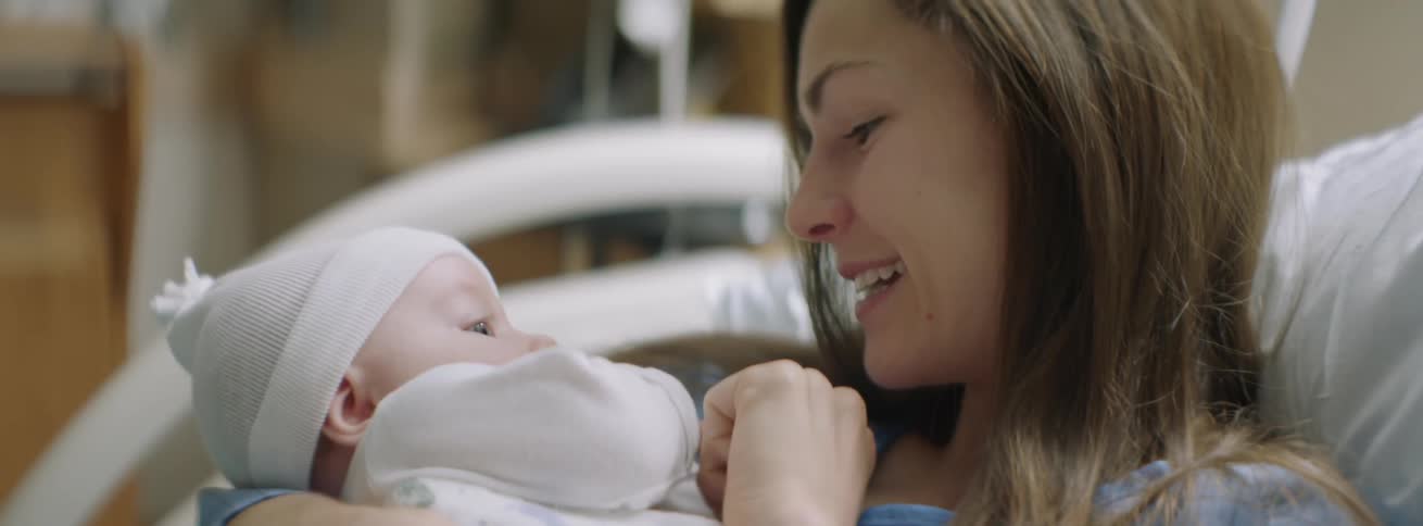 A woman in a hospital bed holds her baby