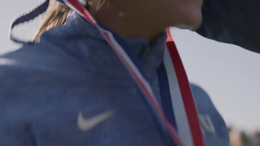 A woman smiles as she is given a winning medal