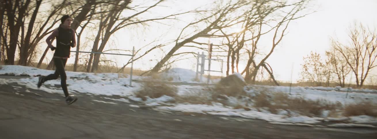 Woman runs on an outdoor rural road at sunset