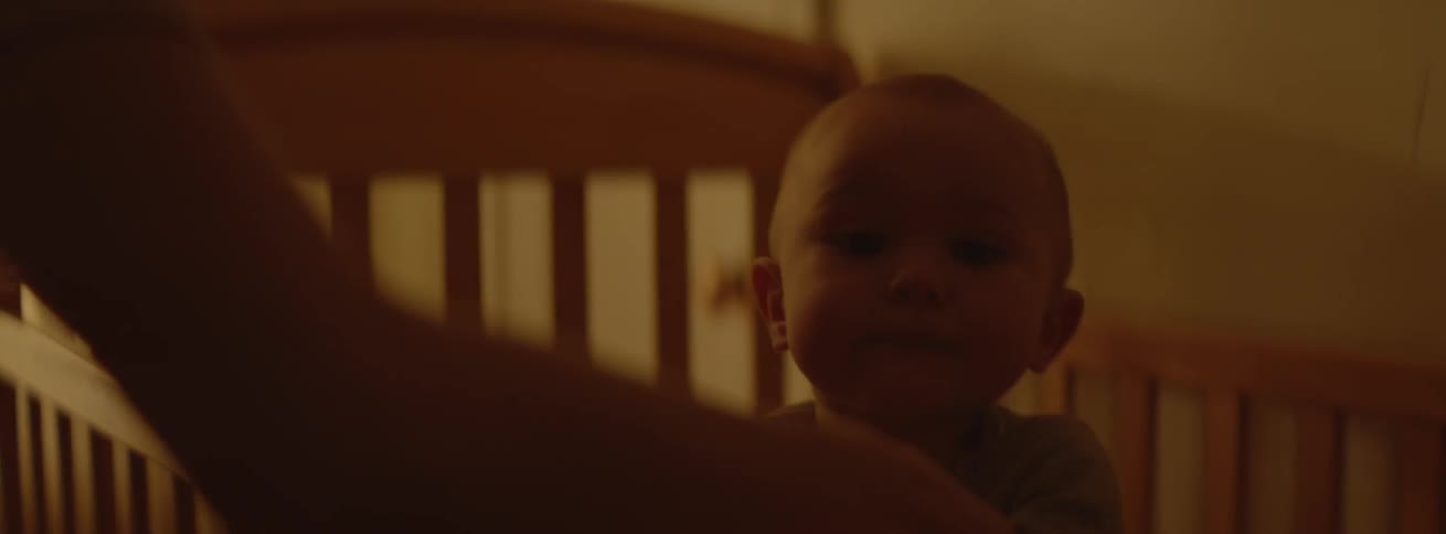 A baby jumps around in the crib, and is kissed on the forehead