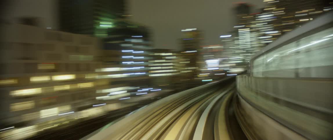 A commuter train is traveling on an elevated track in a city at night