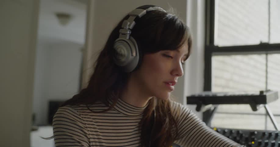 A woman is working in a studio wearing headphones