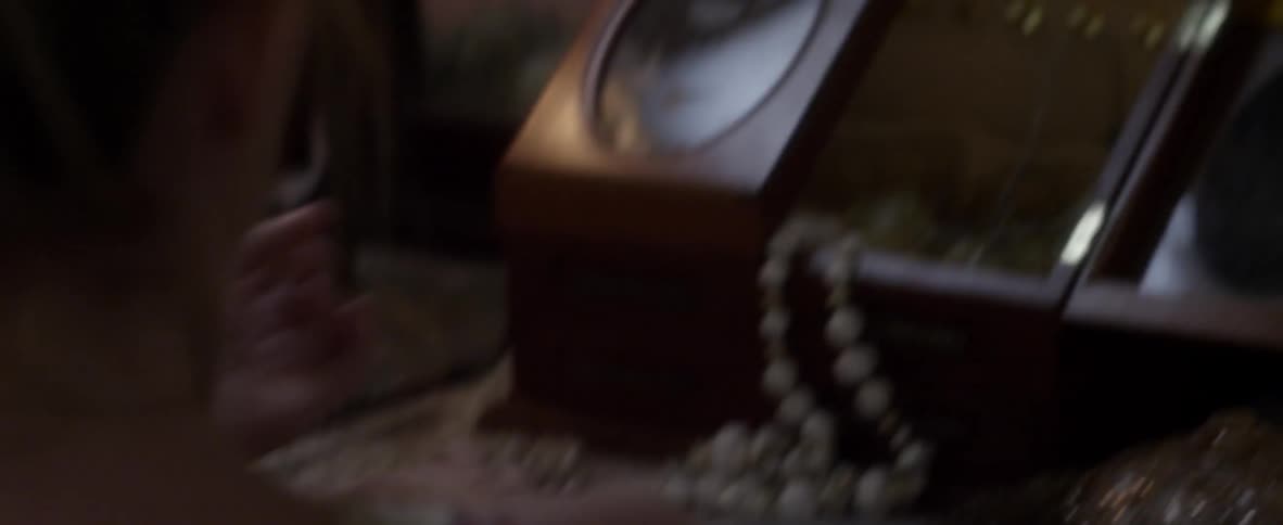 A woman sitting at her dressing table looking at her reflection notices the time and rushes out