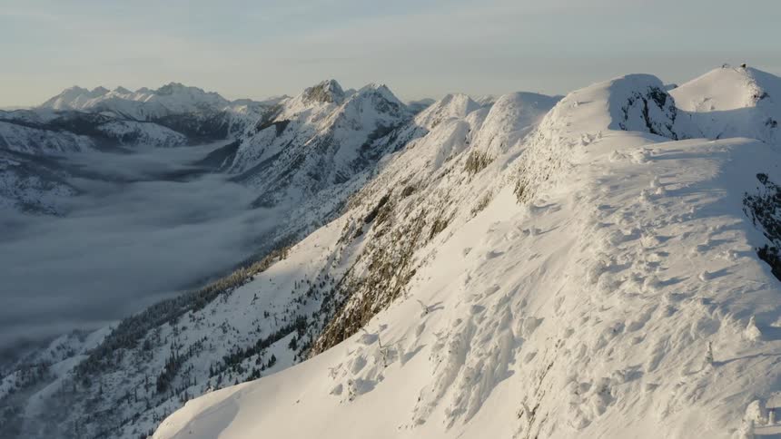 Sunlight is streaming onto a mountain range covered in snow