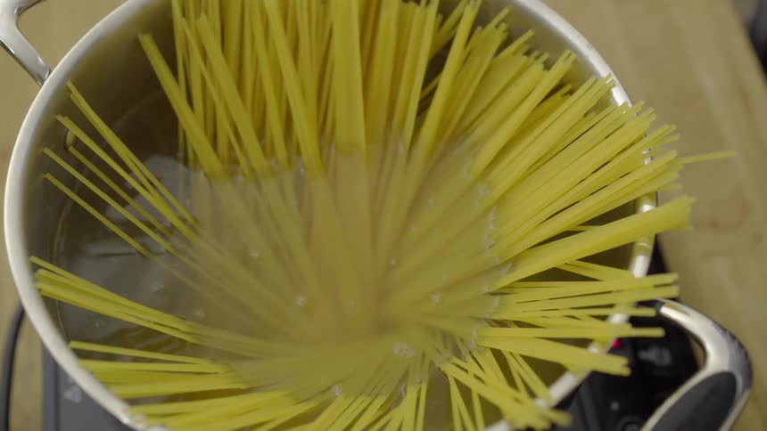 Pasta being thrown into a pot of boiling water