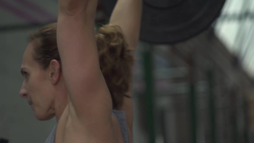 A woman lifts a barbell overhead
