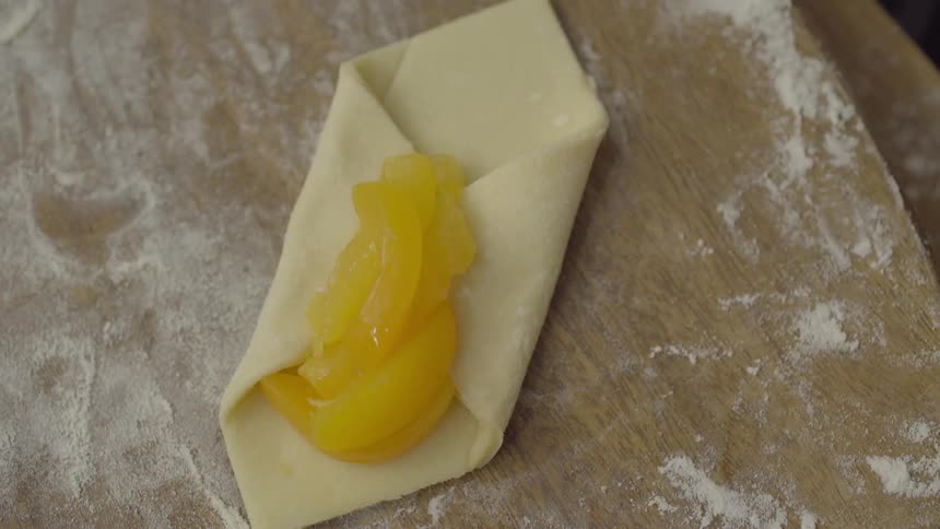 Someone making a pastry with dough and fruit