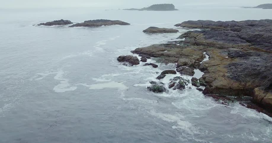The waves crash against the shore on a foggy day