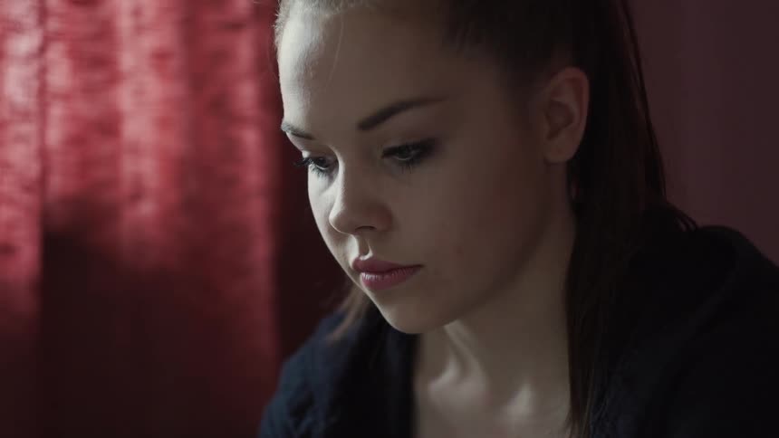 Girl sits indoors looking down