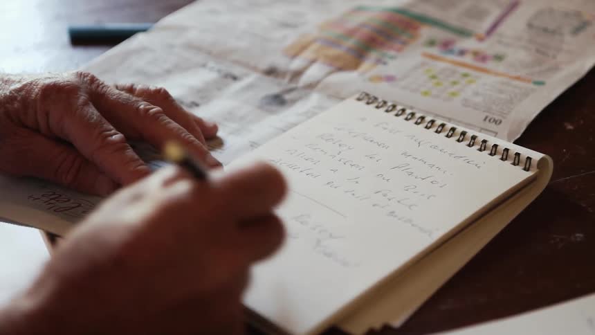 Man writes in a coiled notebook with a pen