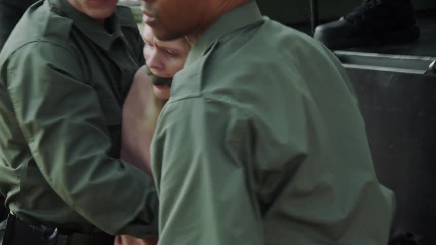 Soldiers escort two prisoners from a truck bed