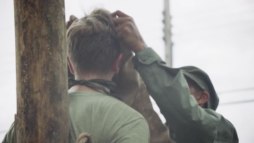 A soldier puts a bag over a prisoner's head